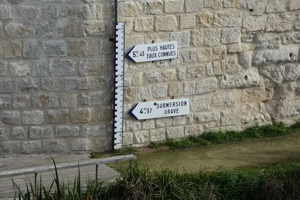 Échelle de crue et panneaux « plus hautes eaux connues » et « submersion grave » sur un mur de quai à Soissons