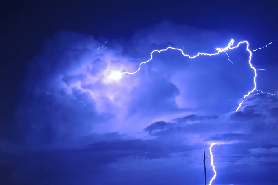 Un éclair zébrant le ciel nocturne sous un nuage d'orage éclairé de l'intérieur